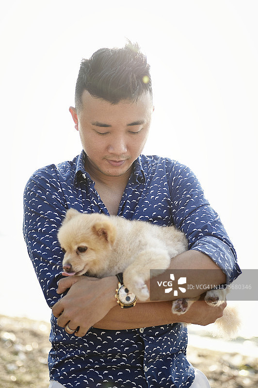 英俊的亚洲男人和他的狗在海滩上图片素材