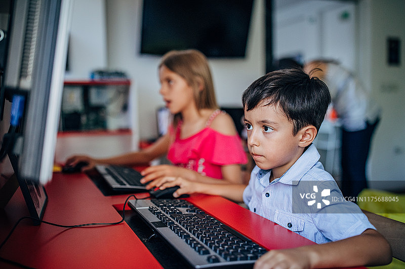 小男孩和小女孩在小学使用电脑图片素材