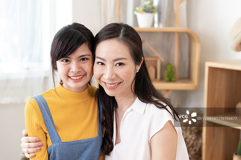 微笑的亚洲家庭的肖像母亲和十几岁的女儿拥抱在一起看着你在一个房间的自然阳光在家。展示爱心，母亲节快乐的理念图片素材
