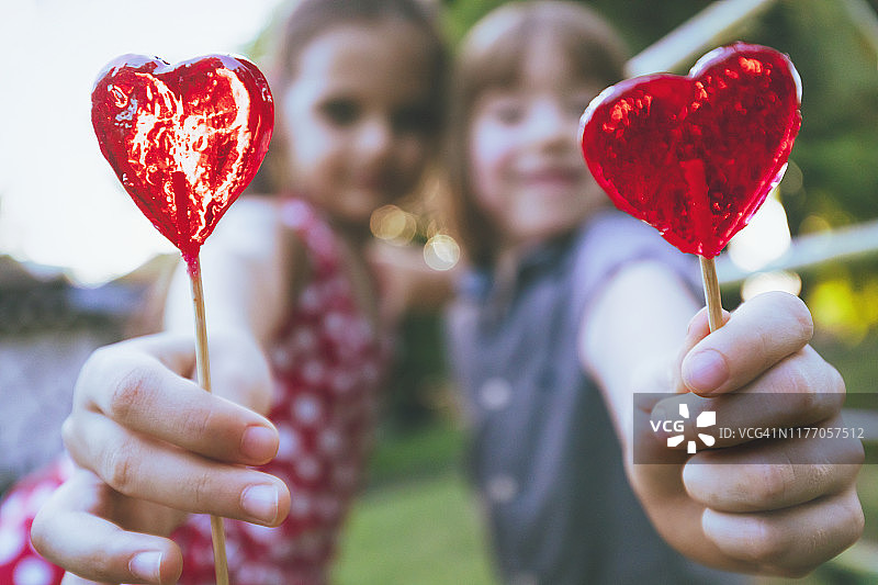 孩子们拿着棒棒糖玩得开心。情人节。图片素材