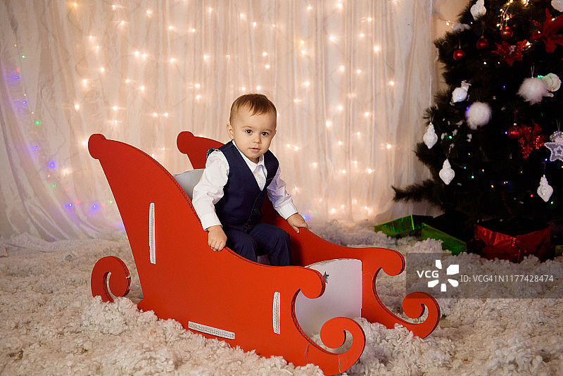 小男孩穿着万圣节服装在圣诞树旁等待圣诞节的到来图片素材