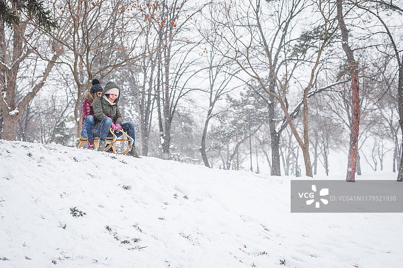 年轻女子滑着雪橇下山图片素材