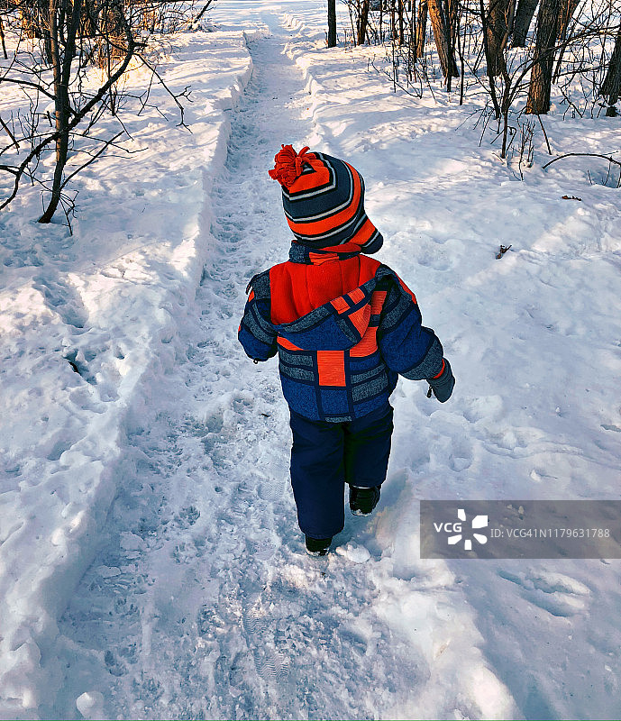 小男孩探索积雪覆盖的小路图片素材