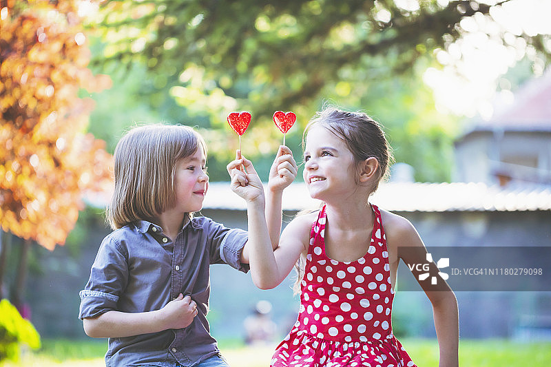 孩子们拿着棒棒糖玩得开心。爱的概念。图片素材
