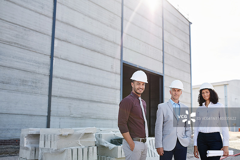 三个不同的建筑工程师微笑着站在一个工地上图片素材