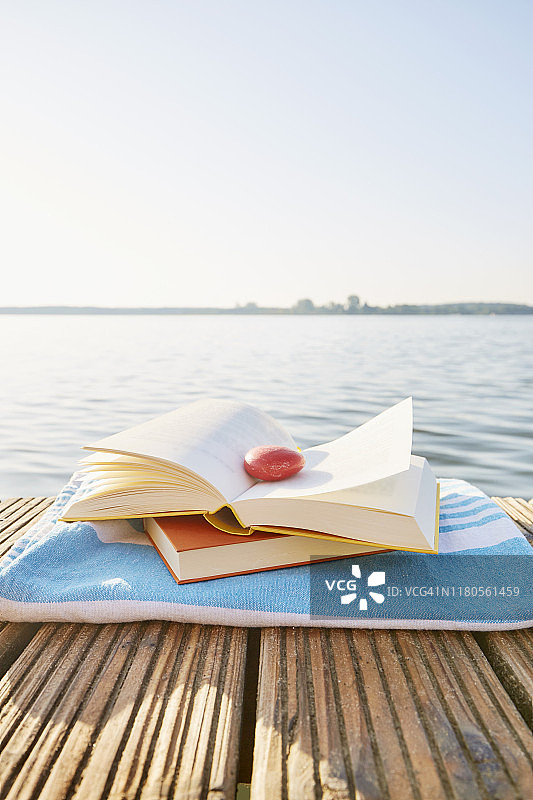 一本书的静物生活与一个红色的石头作为书签在码头上的一个湖，宁静的景象图片素材