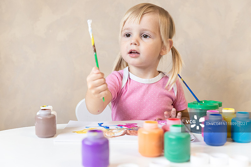 可爱的小女孩画流苏和颜料。的童年。艺术图片素材