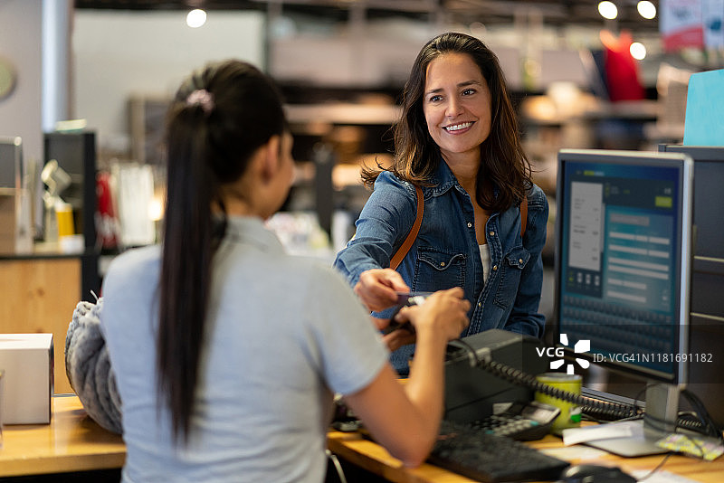 一位快乐的女顾客微笑着用信用卡进行非接触式支付图片素材