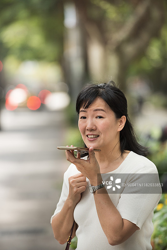 台北一名女子拿着手机在街上走路图片素材