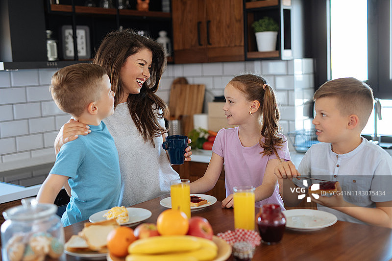 妈妈和三个孩子在厨房里吃早饭图片素材