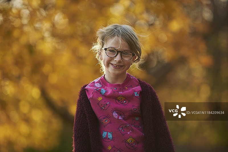 可爱的年轻女孩的肖像微笑周围五颜六色的树。图片素材