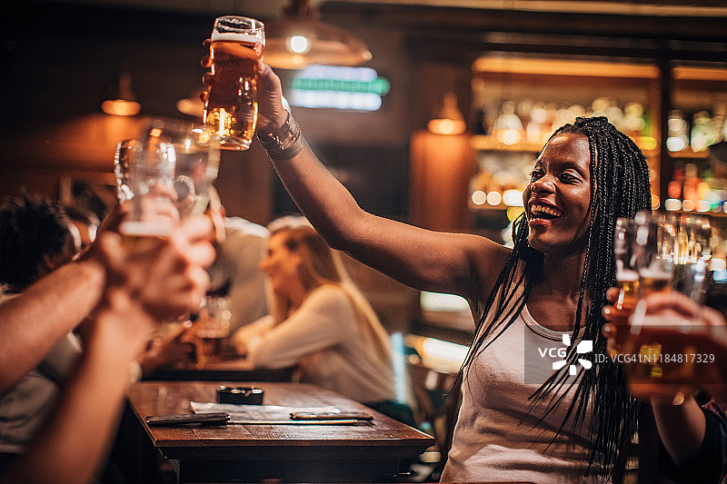 在酒吧里喝啤酒的黑人妇女图片素材