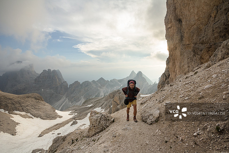 背包客攀登崎岖的小径，越过遥远的山峰图片素材