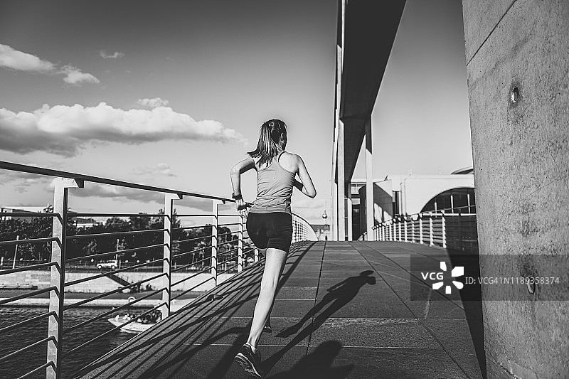 年轻的女运动员正在柏林的一座桥上奔跑图片素材