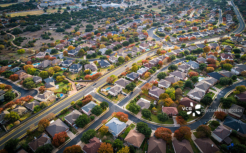 在郊区现代住宅开发中，无人机俯瞰秋天的色彩图片素材