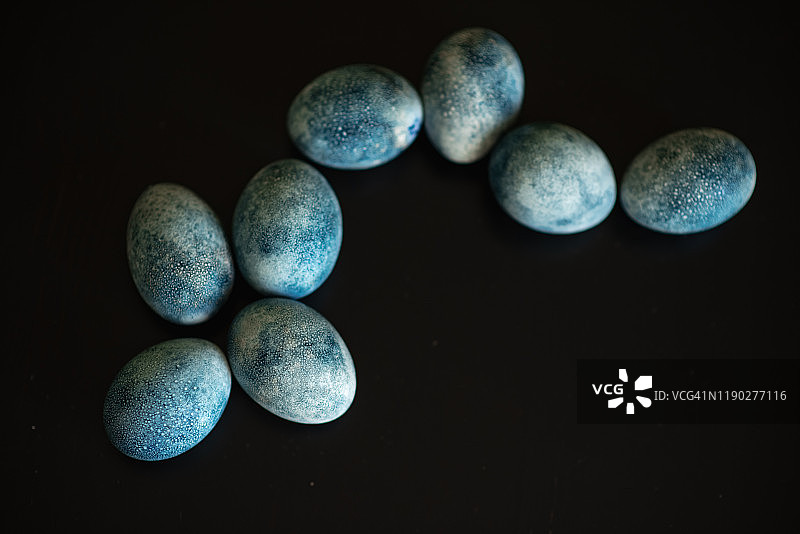 用手工在暗色背景上画上蓝色的巢中的复活节彩蛋。鸡和鹌鹑蛋天主教和东正教复活节图片素材