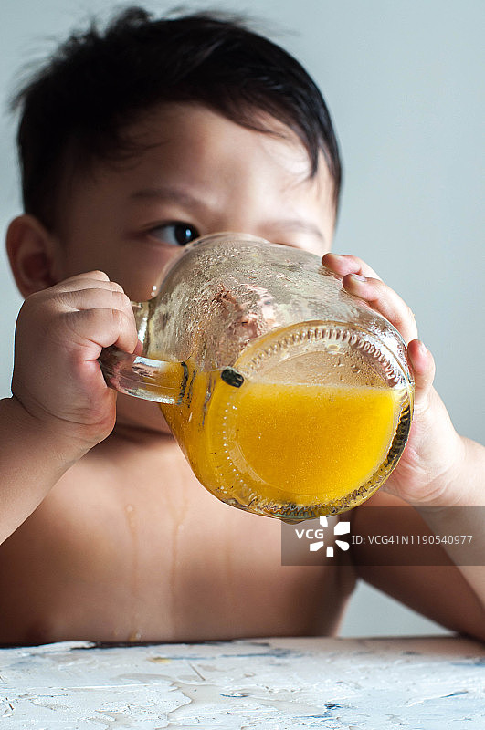 一个亚洲男孩正在喝黄色的西瓜汁图片素材