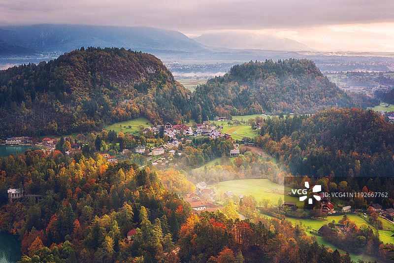 风景鸟瞰流血在朱利安阿尔卑斯山日落，斯洛文尼亚。令人惊叹的秋季景观，阳光明媚的山谷，高山村庄和山脉图片素材