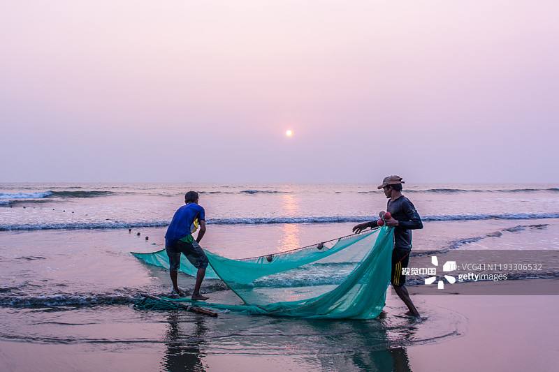 在孟加拉国的考克斯巴扎尔，两名渔民在夕阳下捕鱼图片素材