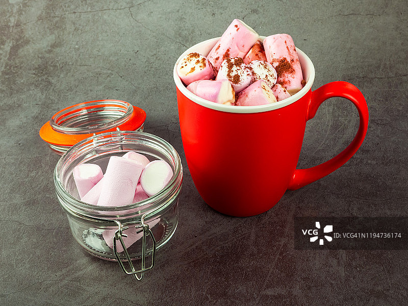 一个红色的陶瓷碗，里面放着热巧克力和棉花糖，放在玻璃罐里图片素材
