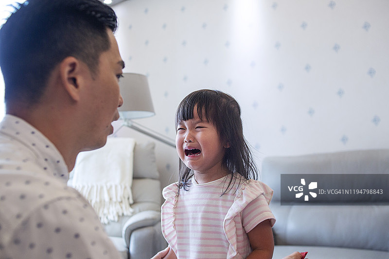 亚洲父亲安慰哭泣的女儿的特写图片素材
