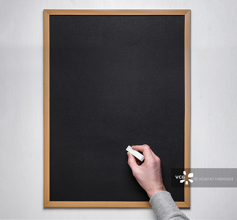 男用粉笔在空黑板或黑板上写字。图片素材