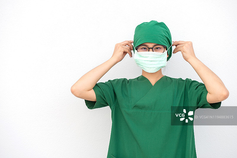 年轻亚洲护士身穿外科医生制服，佩戴外科口罩，以防止吸入空气中的细菌或病毒疾病。图片素材