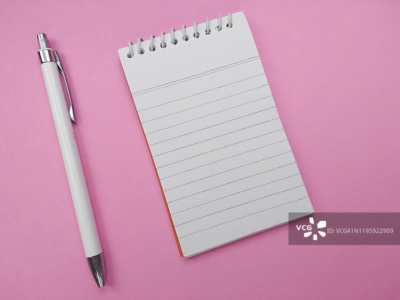 螺旋记事本，日记和钢笔孤立在粉红色的背景。图片素材
