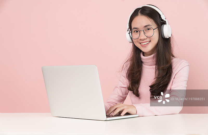 回到学校教育知识学院大学理念，美丽微笑的女学生使用在线教育服务，快乐的亚洲女人放松和听音乐与电脑笔记本电脑图片素材