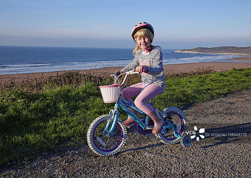 女孩(4-5岁)骑着带稳定器的自行车俯瞰海滩图片素材