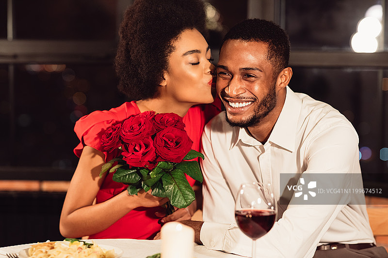 在餐厅约会时，女友收到玫瑰后亲吻男友图片素材