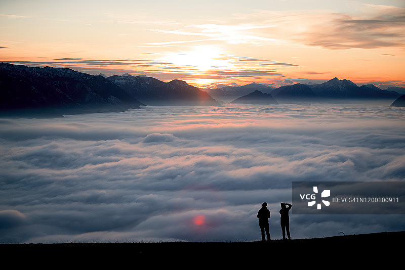 两个女人的剪影在日落看风景的山峰上，萨尔茨堡，奥地利图片素材