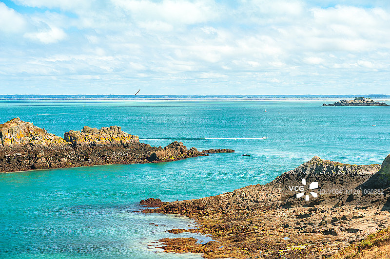 在阳光明媚的蓝天下，可以看到海洋、海岸、布里塔尼海岸的Pointe du Grouin碧绿的海水和岩石图片素材