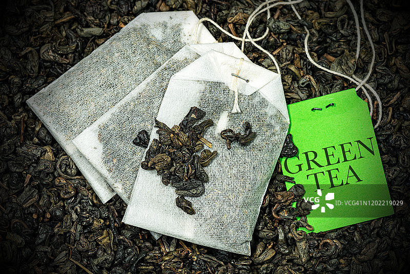 许多干茶叶上的绿茶袋的特写-火药茶图片素材
