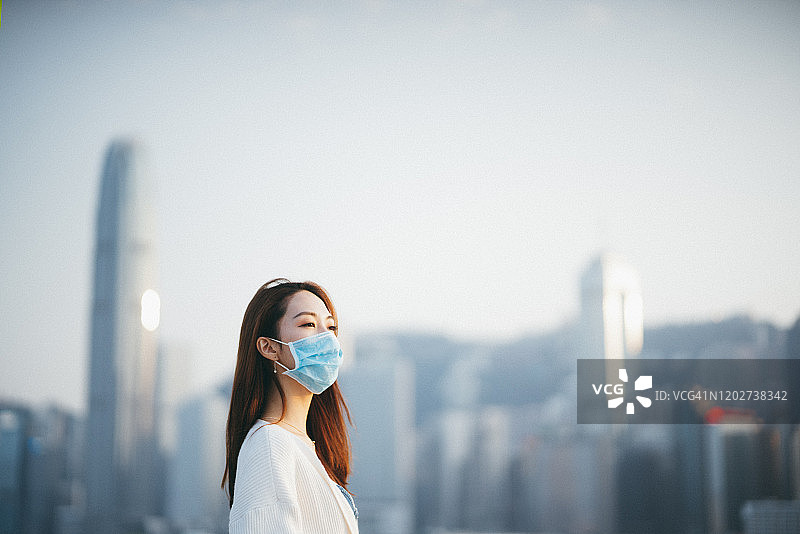 一名年轻的亚洲女子戴着防护口罩，以防止冠状病毒的传播，这是一场全球卫生紧急事件的爆发图片素材