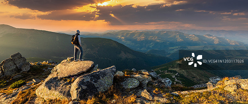 一个年轻人在山顶上看日落图片素材