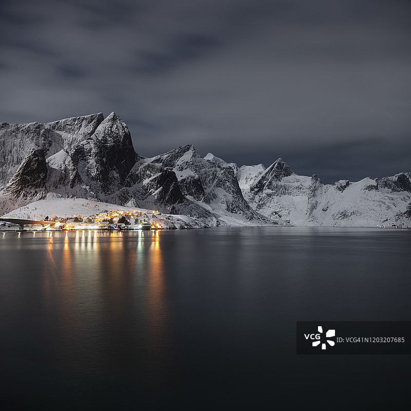 挪威罗浮敦群岛莫斯克尼西勒内附近的村庄灯光在冬夜的月光下闪闪发光图片素材
