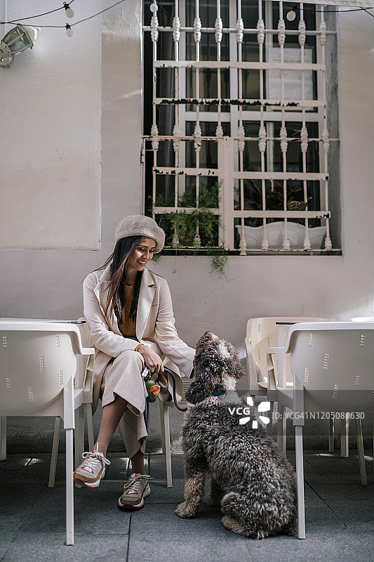 一位年轻女子和她的狗坐在城里的一家咖啡馆里图片素材
