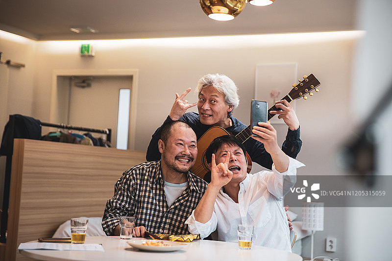 成熟的韩国男人在家里玩吉他和唱歌图片素材