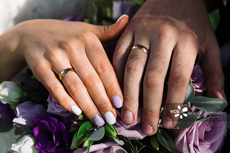 漂亮的手和新婚夫妇的结婚戒指在一个花束图片素材