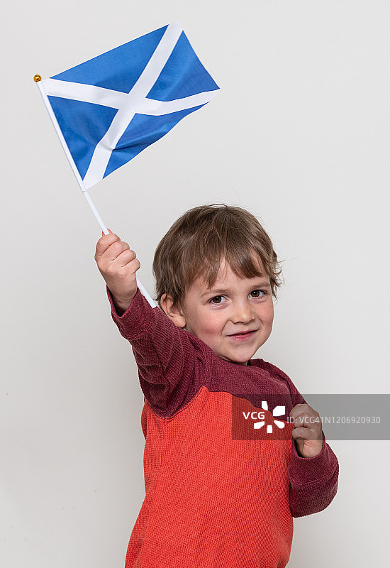 微笑的白人男孩看着镜头举着苏格兰国旗图片素材
