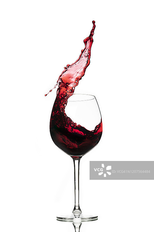 在白色背景下，红酒在玻璃杯中溅起。副本的空间。图片素材
