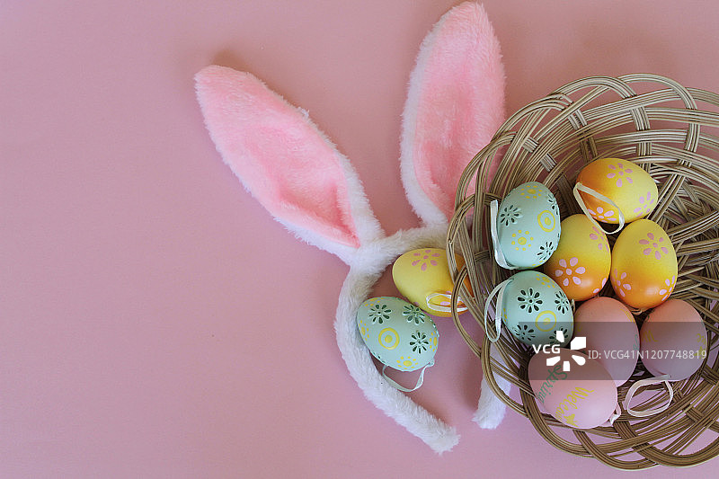 粉色背景上的复活节彩蛋和兔子耳朵。平躺图片素材
