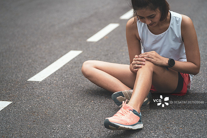 膝盖疼痛。运动损伤，女性在户外运动时膝盖疼痛。运动中女子跑步膝盖受伤。图片素材