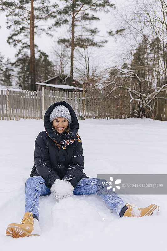 快乐的女人坐在雪地上玩雪球图片素材