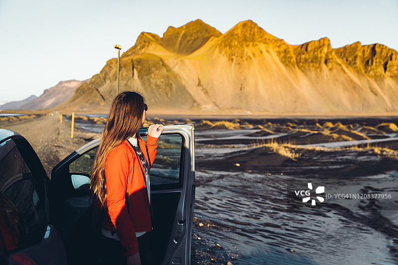 在冰岛风景秀丽的海滩上，女人呆在汽车附近，迎接灿烂的日出图片素材