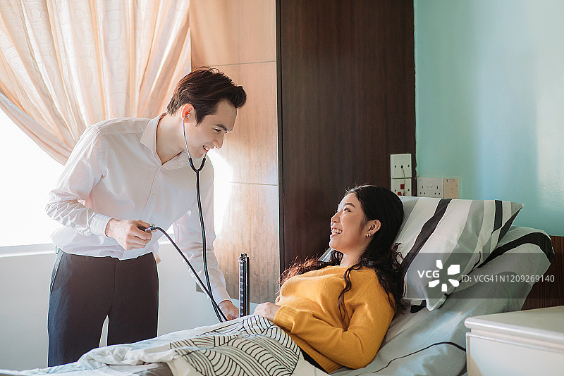 亚洲华人男医生在医院用听诊器为病人检查心跳和测量血压图片素材