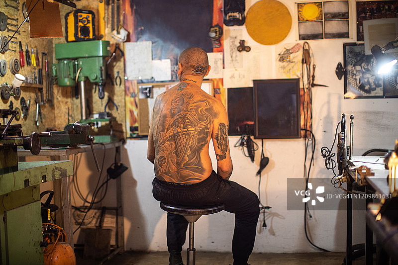 纹身艺术家与纹身头坐在他的工作室，看他的艺术作品图片素材