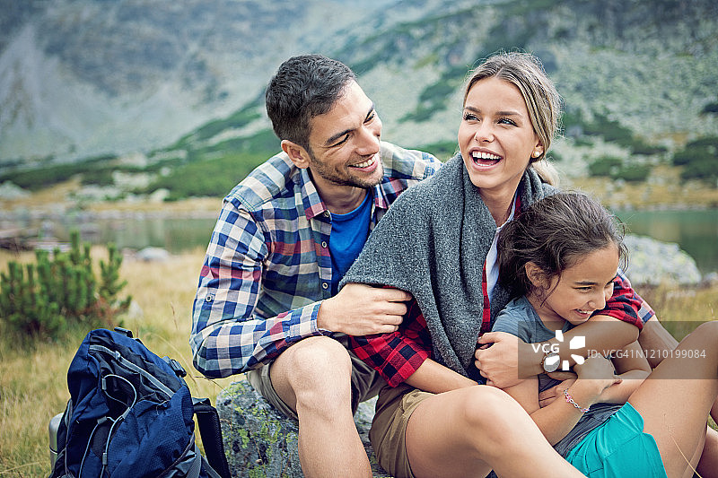 快乐的徒步旅行家庭在山上的湖边放松和拥抱图片素材