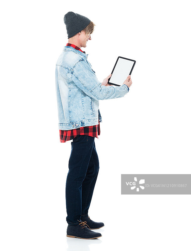 白人潮男穿着牛仔裤站在白色背景前使用触摸屏图片素材